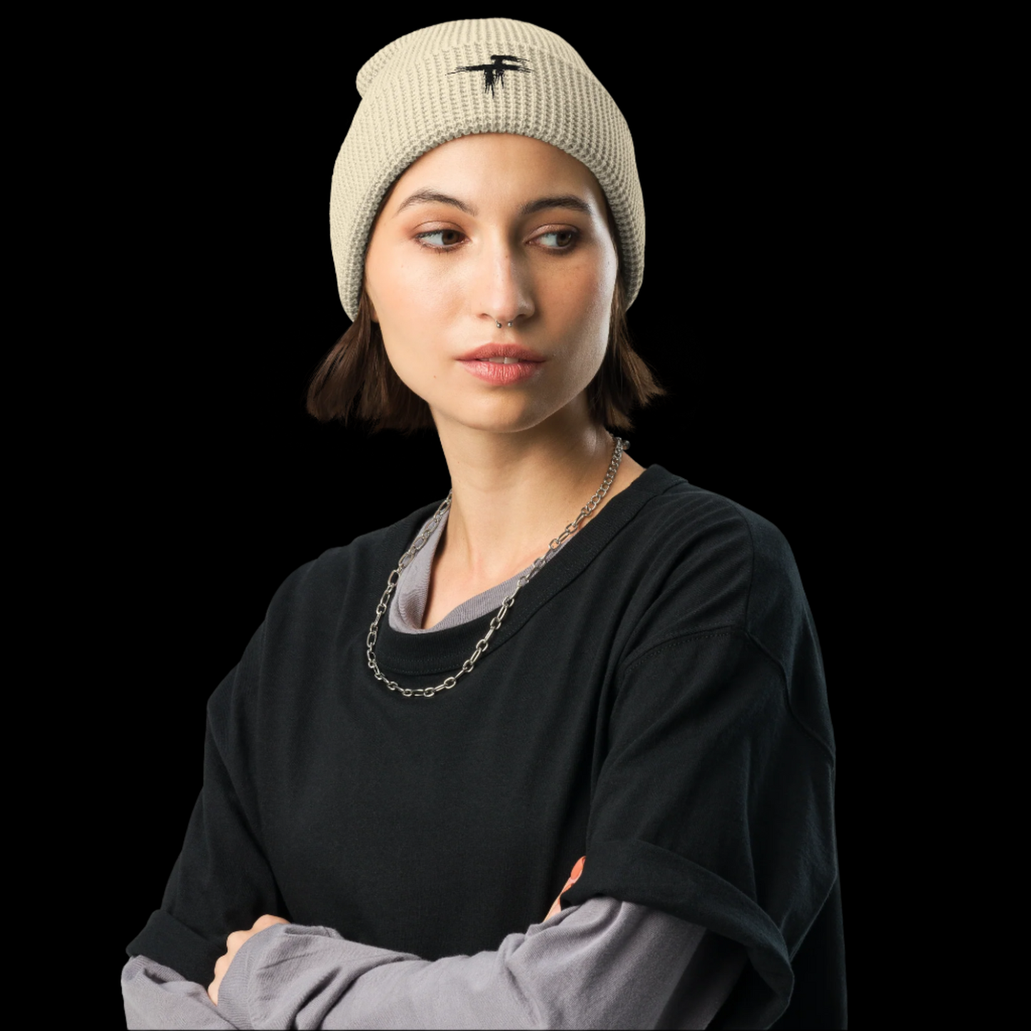Woman wearing a beige beanie and black sweater with arms crossed